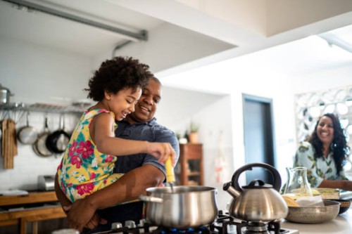 girl in father's arms helping him cooking at home - food stock pictures, royalty-free photos & images