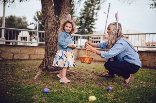 girl looking for eggs during easter egg hunt with grandmother - garden decoration stock pictures, royalty-free photos & images