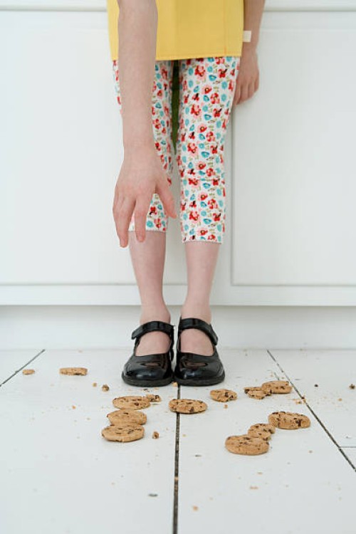 girl reaching for cookies on a floor - food stockfoto's en -beelden