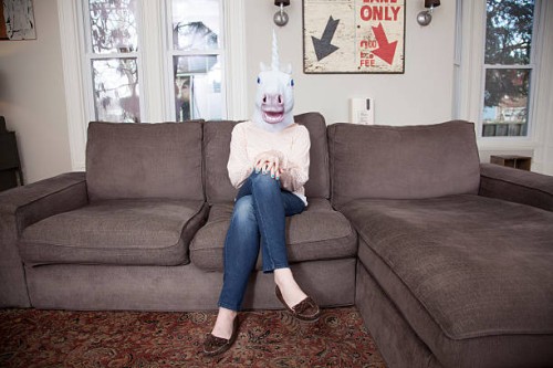 girl sitting on sofa wearing unicorn head mask - home decoration stock pictures, royalty-free photos & images