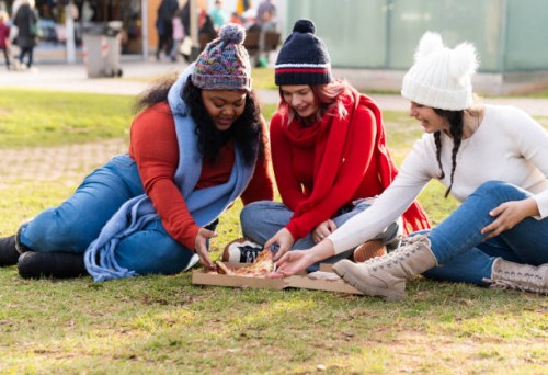 girls eating pizza in a park - junk food stock pictures, royalty-free photos & images