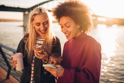 girls using phone and having a snack - junk food stock pictures, royalty-free photos & images