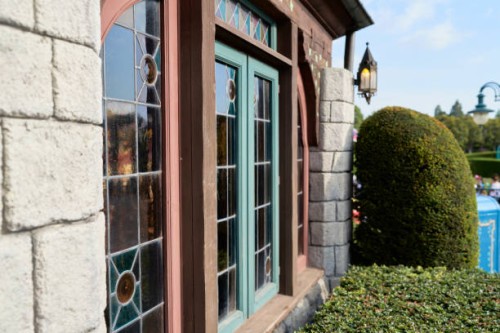 glass window and wooden frames, in stone wall, antique design, bushes and clear sky. - garden decoration stockfoto's en -beelden
