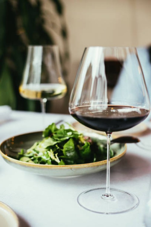 glasses of red and white wine and green salad on table - food stock pictures, royalty-free photos & images