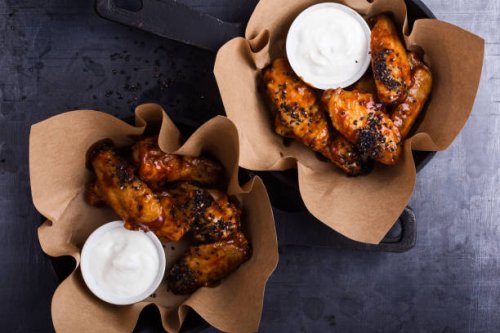 glazed spicy chicken wings with sesame seeds served in cast iron skillets - junk food stock pictures, royalty-free photos & images