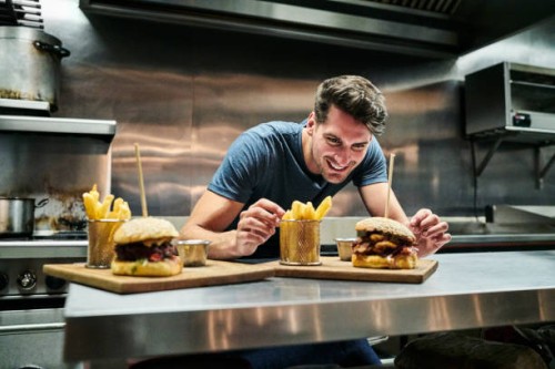 glimlachend chef-kok te kijken naar voedsel geserveerd op counter - junk food stockfoto's en -beelden