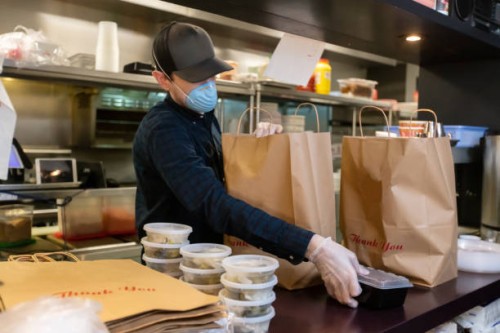 gloved and masked man in restaurant kitchen preparing food for delivery during covid-19 pandemic - junk food stock pictures, royalty-free photos & images