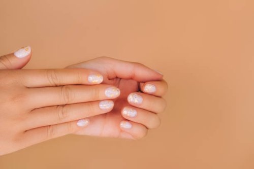 glowing hands with nude color manicure with gold particles on beige background. trendy colors of the year - nails art stock pictures, royalty-free photos & images