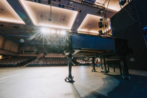 grand piano on stage with choir contestants seating at bleacher in theatre auditorium - concert stock pictures, royalty-free photos & images