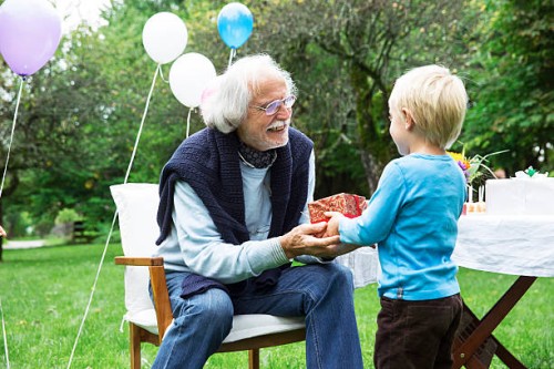 grandfather receiving gifts on birthday party in garden - garden decoration stock pictures, royalty-free photos & images