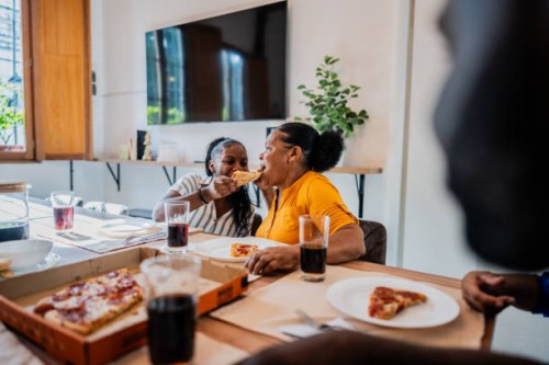 grandmother and granddaughter eating pizza at home - junk food stock pictures, royalty-free photos & images