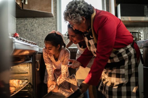 grandmother, mother and daughter looking at food in the oven at home - food stock pictures, royalty-free photos & images