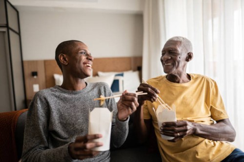 grandson and grandfather talking and eating take out food at home - junk food stock pictures, royalty-free photos & images