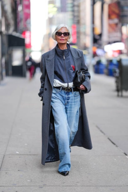 Grece Ghanem wears black sunglasses, dark navy blue white zipped high neck jacket, dark blue double breasted wool coat, shiny black Calvin Klien...