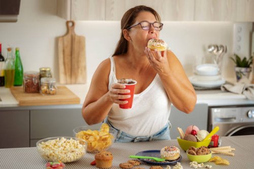 greedy woman enjoying eating a doughnut and drinking cola. unhealthy eating concept - junk food stock pictures, royalty-free photos & images