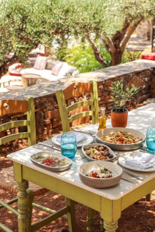 greek dinner table with food and plates under olive trees with cretan delicacies - food stock pictures, royalty-free photos & images