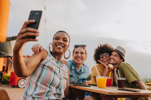 group of friends at table taking selfie - travel stockfoto's en -beelden
