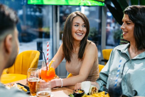 group of friends drinking and eating burgers and tortilla wraps in a bar indoors - junk food stock pictures, royalty-free photos & images