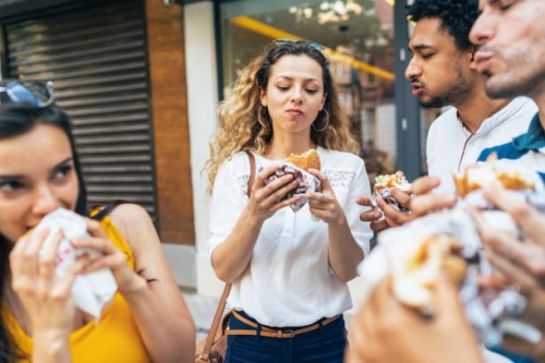 group of friends eating burgers - junk food stock pictures, royalty-free photos & images