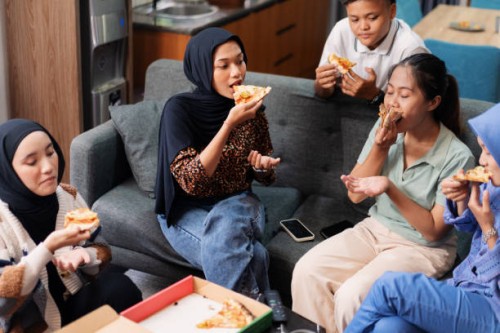 group of friends enjoying pizza together in casual indoor setting - junk food stock pictures, royalty-free photos & images