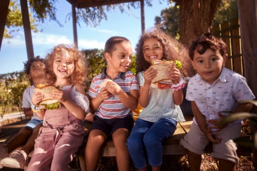 group of happy children sitting eating sandwiches in the garden - food stock pictures, royalty-free photos & images