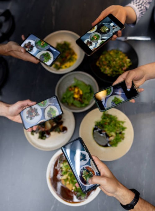 group of people eating at a restaurant and taking pictures of their food - food stock pictures, royalty-free photos & images