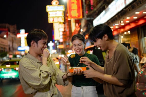 group of travelers delighting in thai street food at china town night market. - food stock pictures, royalty-free photos & images