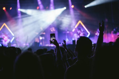 group of unrecognizable people enjoying a music concert while one of them takes a picture with his cell phone. - concert stock pictures, royalty-free photos & images