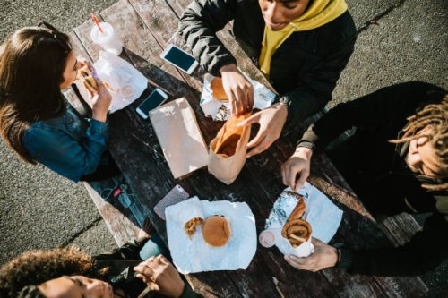 group of young adults eating fast food - junk food stock pictures, royalty-free photos & images