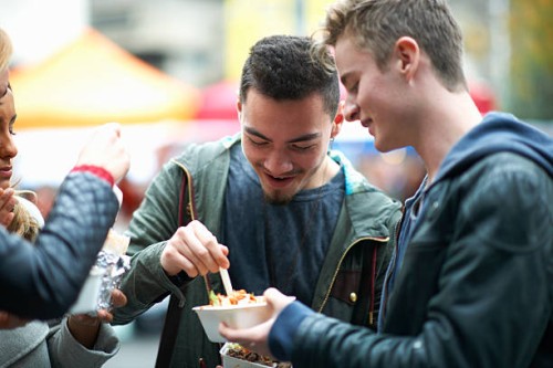 group of young adults eating takeaway food, outdoors - junk food stock pictures, royalty-free photos & images
