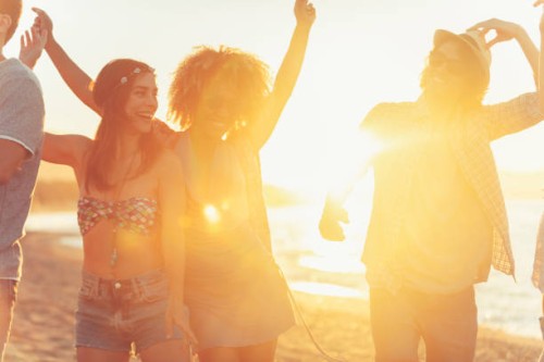 gruppe von freunden tanzen und feiern am strand bei sonnenaufgang / sonnenuntergang. - concert stock-fotos und bilder