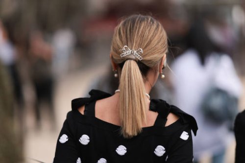 Guest is seen outside Chanel show wearing a silver Chanel bow hair detail and black Chanel top with white camellia details during the Womenswear...