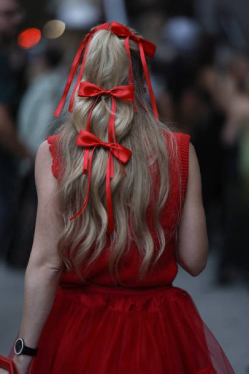 Guest is seen outside Khaite show wearing red bows in her hair, red dress on September 09, 2023 in New York City.