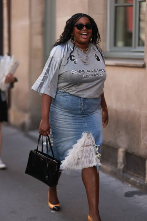Guest is seen outside The Row show wearing golden earrings and necklaces oversized grey sports Comme des Garcons t-shirt with denim pencil skirt with...