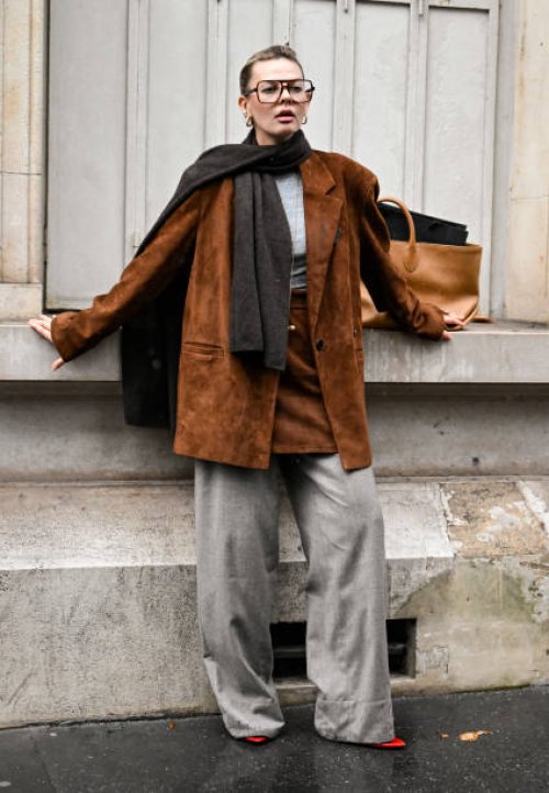 Guest is seen wearing a beige jacket, beige skirt, gray pants and brown scarf outside the Uma Wang show during Womenswear Spring/Summer 2025 as part...