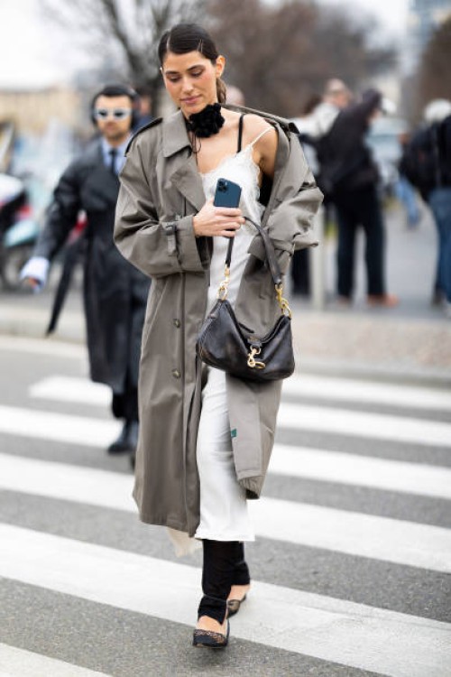 Guest is seen wearing a black choker embellished with a black fabric flower, a black bra, a beige long trench, a white long sleep-dress embellished...
