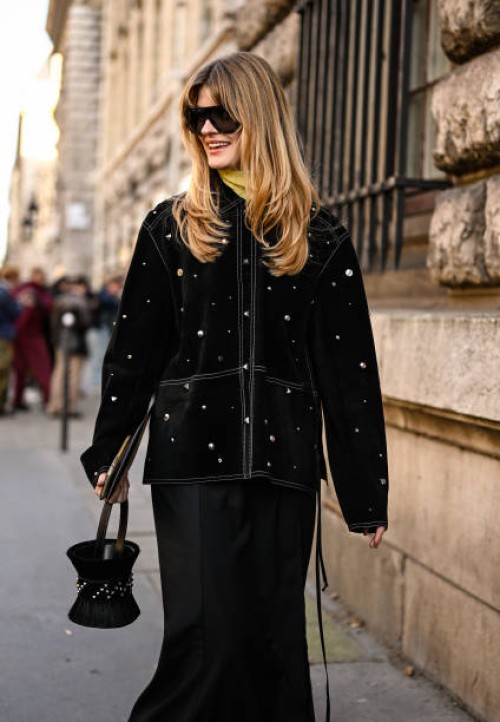 Guest is seen wearing a black embellished coat, black skirt, black and jeweled bag with black sunglasses outside the Hermes show during the...