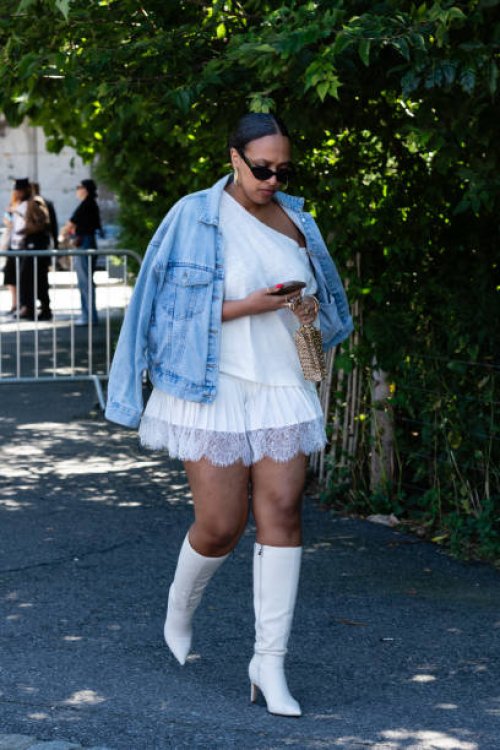 Guest is seen wearing a blue denim jacket, white top, white skirt, white boots, black sunglasses and carrying a gold bag outside the Off-White show...