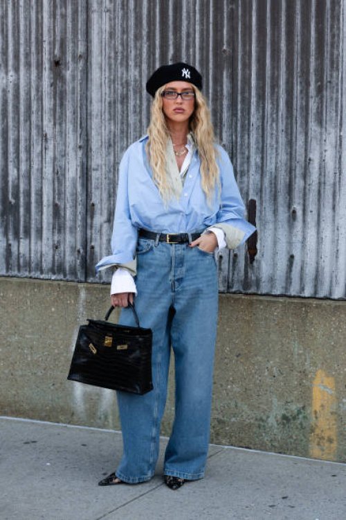 Guest is seen wearing a blue shirt, blue denim pant, black lace heels, black hat and carrying a black bag outside the COS show during New York...