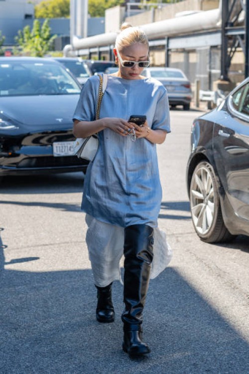 Guest is seen wearing a blue top, black boots, white sunglasses and carrying a white bag outside the COS show during New York Fashion Week on...