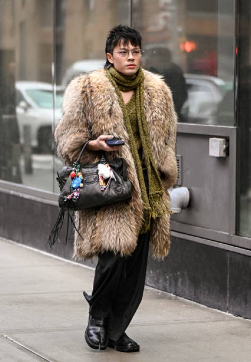 Guest is seen wearing a faux fur tan coat, black bag, black pants, black shoes and green scarf outside the Christian Siriano show during NYFW F/W...