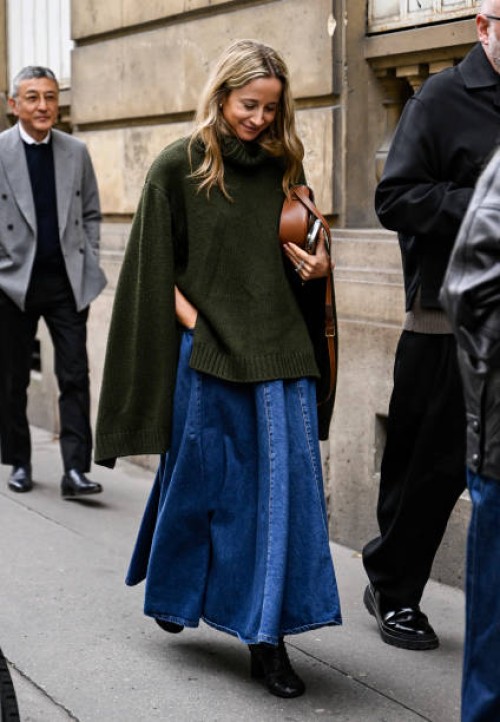 Guest is seen wearing a green sweater, denim skirt, brown bag and black shoes outside the Gabriela Hearst show during Womenswear Spring/Summer 2025...