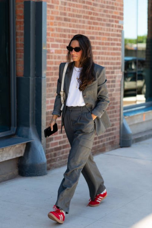Guest is seen wearing a grey blazer, white top, grey pant, red shoes, black sunglasses and cream bag outside the Ulla Johnson show during New York...
