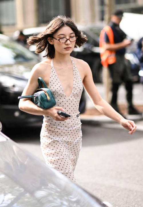Guest is seen wearing a Miu Miu white and black polkadot dress with a green Miu Miu bag and glasses outside the Miu Miu show during the Womenswear...