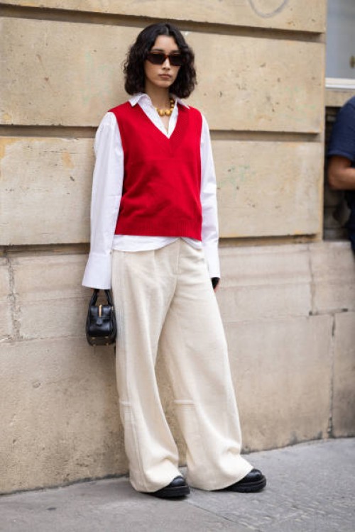 Guest is seen wearing a red sweater vest over a white button shirt and wide pants outside Marni show during the Womenswear Spring/Summer 2024 as part...