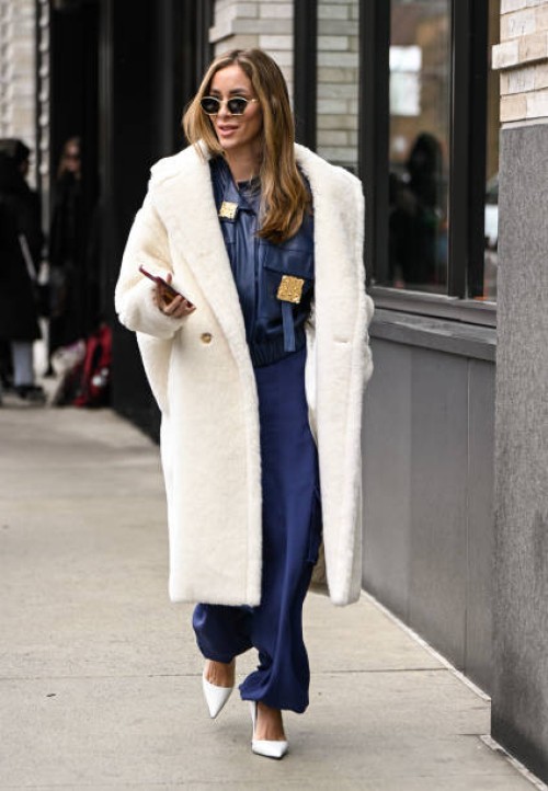 Guest is seen wearing a white coat, blue and gold embellished top, blue pants, white heels and gold sunglasses outside the Ulla Johnson show during...