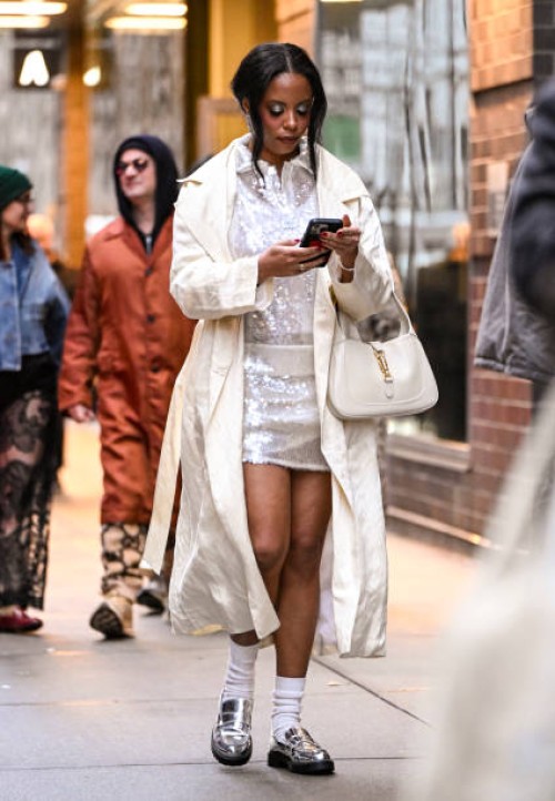 Guest is seen wearing a white rain coat, sequin top and skirt, metallic shoes and cream bag outside the Christian Siriano show during NYFW F/W 2025...