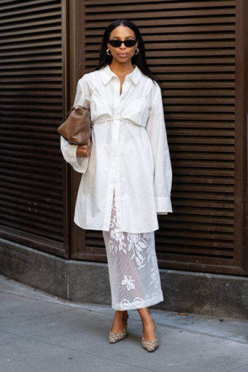 Guest is seen wearing a white shirt, white bra top, white lace skirt, brown heels and carrying a brown bagoutside the Patbo show during New York...