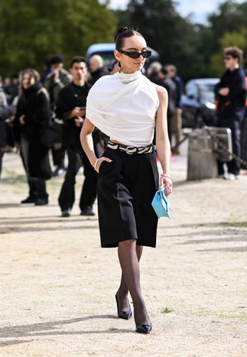 Guest is seen wearing a white top, black shorts, black heels, teal mini-bag and zebra print belt outside the Loewe show during Womenswear...