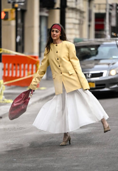 Guest is seen wearing a yellow jacket, white skirt, tan shoes and burgundy bag with burgundy headband outside the Altuzarra show during NYFW F/W 2025...